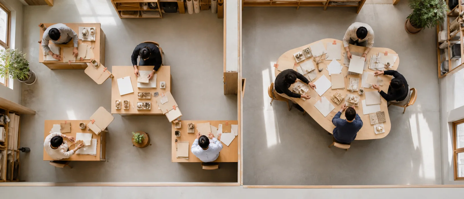 AI-generated overhead photograph contrasting separate desks reporting inward with collaborators working around one shared table