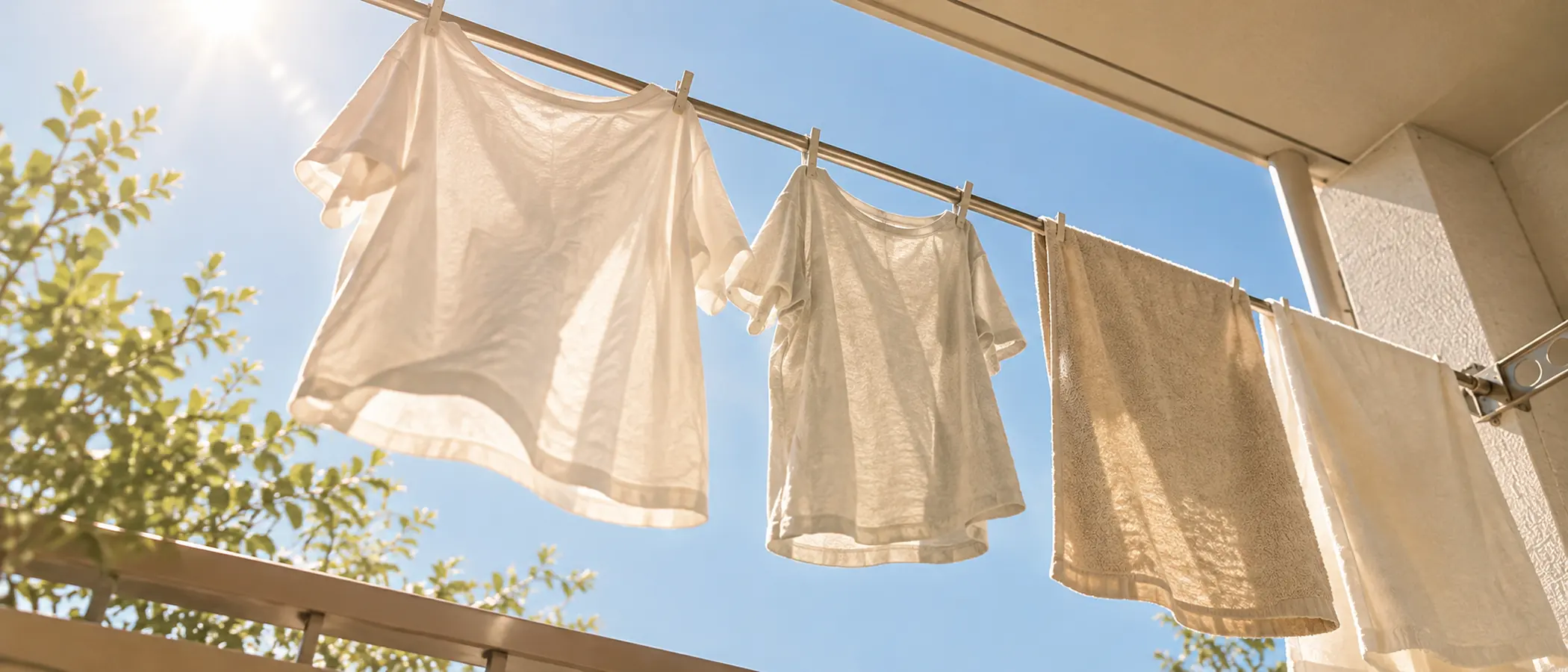 AI-generated view looking up at two shirts of different sizes and towels drying side by side on a balcony clothesline on a sunny day